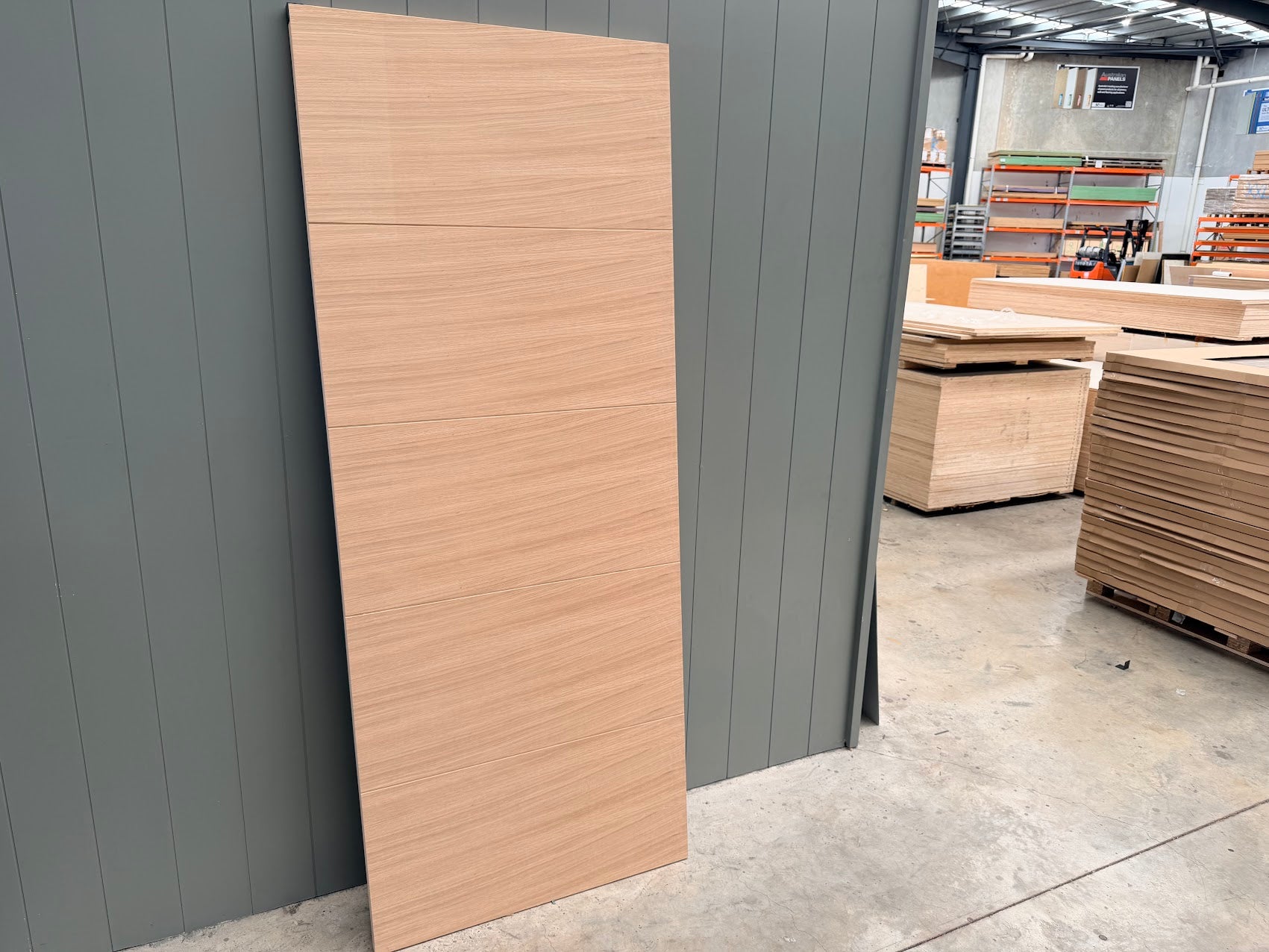 Internal white oak wooden door natural timber grain finishleaning against a gray wall in an indoor setting