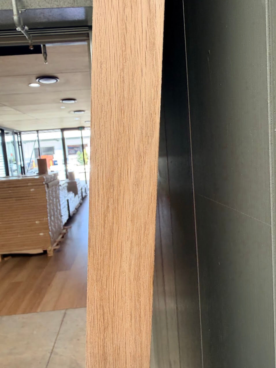 Internal white oak wooden door and black wall in an indoor setting