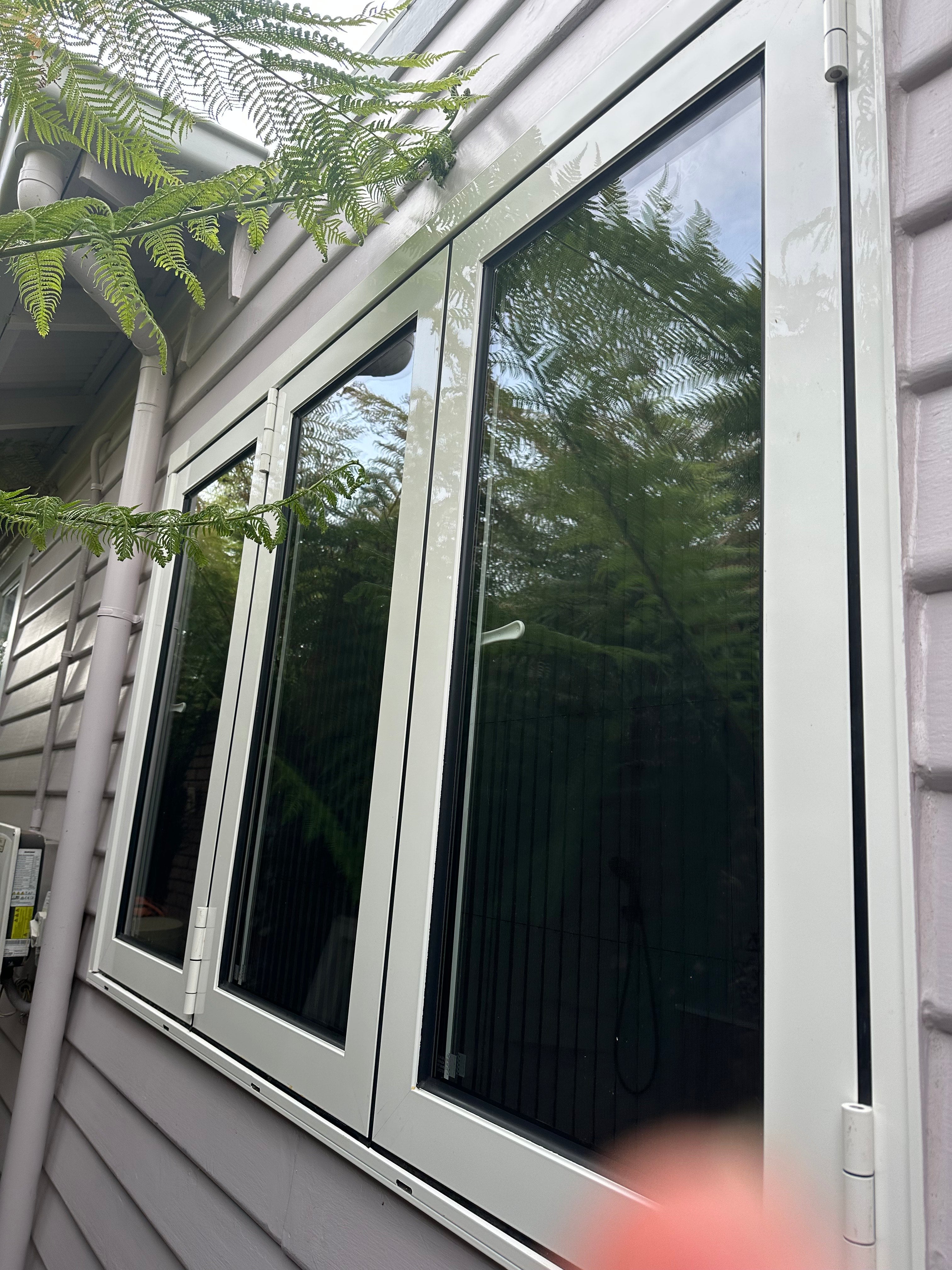 Ceiling with a large bifold window, reflecting trees and sky.